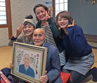 米寿お祝いにご自分の名前にちなんだ言葉の似顔絵を持って嬉しそうなおじいちゃんの記念写真