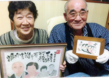 似顔絵を手に喜ばれている、おじいちゃん。おばあちゃんの記念写真